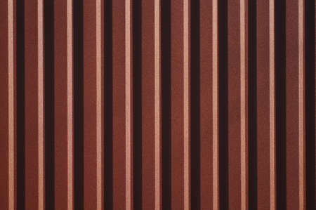 Background with symmetrical brown straight lines. Trapezoidal sheet metal wall. Metal sheet metal design in embossed pattern. Simple decorative stencil on corrugated metal sheet.の写真素材