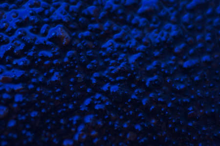Abstract blue mysterious background. Rough texture in dark light. Oily, oily ooze with bubbles and lumps. Dark uneven background with reflected blue light. 3d illustration with gestural texture.の写真素材