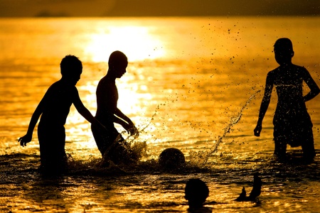 Silhouette of young boys playing during sunset at Koh Samui in Thailandの写真素材