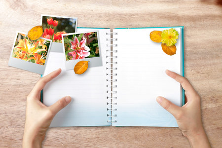 Hands holding note book with photo frame on wood background