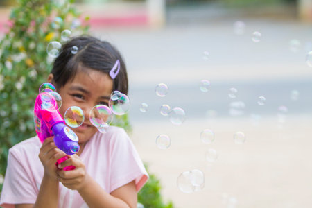 Children Shooting Bubbles from Bubble Gun in the park