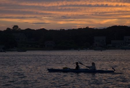These are sea kayakers riding into the harbor in Martha's Vineyard in Silhouette の写真素材