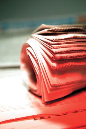 Rolled stack of newspaper under bright red lightの写真素材