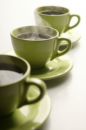Three steaming mugs in a row in green colorsの写真素材