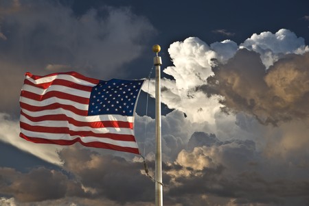 USA flag in the wind dark sky and cloudsの写真素材