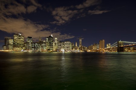 The New York City skyline at night w Brooklyn Bridgeの写真素材