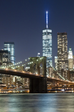 The New York City skyline at night w Brooklyn Bridge and Freedom towerの写真素材