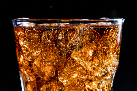 Glass with soft cola drink, ice and bublesの写真素材
