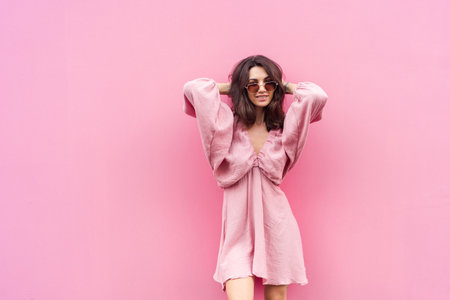 Young beautiful smiling cute romantic woman in trendy summer dress. Carefree woman posing in the street near pink wall. Positive model outdoors in sunglasses. Cheerful and happy.の写真素材