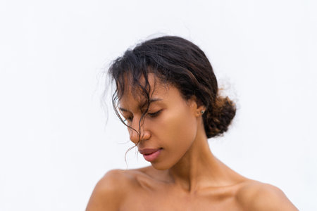 Beauty portrait of young topless african american woman with bare shoulders on white background with perfect skin and natural makeup positiveの写真素材