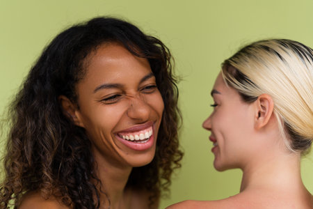Woman close beauty portrait mixed race black skin and white skin, two female on green backgroundの写真素材