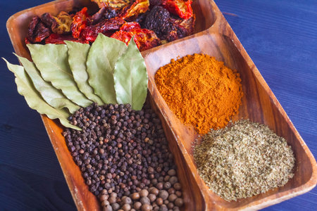spices and herbs on wooden plate on blue backgroundの写真素材