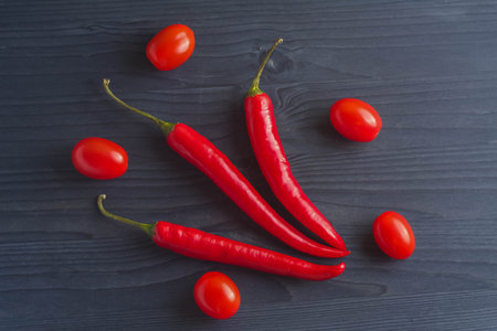 Ripe tomatoes and chili peppers on a wooden countertop blueの写真素材