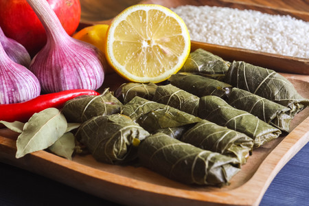 Stuffed delicious dolma with ingredients and lemon on wooden Board on blue backgroundの写真素材