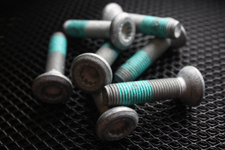 Several bolts covered with blue thread lock on dark background. Blue threadlocker