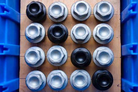 Silver and black wheel bolts in car parts warehouse, top view