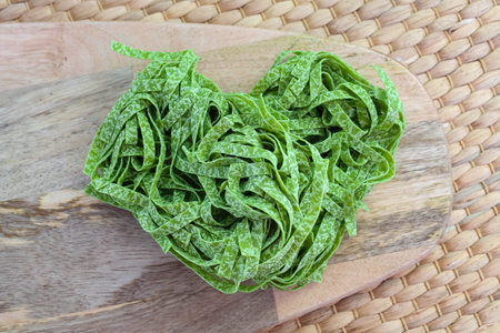 Preparation Italian raw green spinach pasta tagliatelle on a wooden board