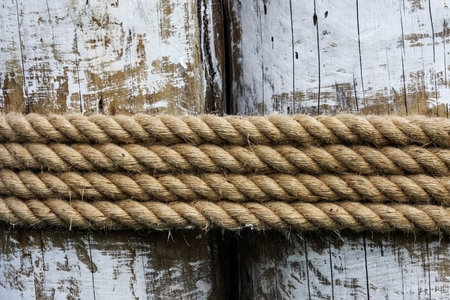 Four layers of rope tied around a wooden log, in the shade on a sunny day