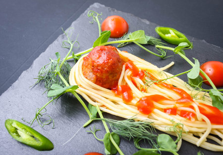 Meat meatballs and spaghetti with herbs were served as a comet with a tail on a basalt plate.