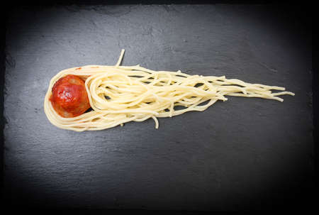 Meat meatball and spaghetti served as a comet with a tail on a basalt plateの写真素材