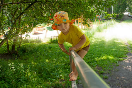 active games in the yard on the street the child climbs on the playground in the summerの写真素材