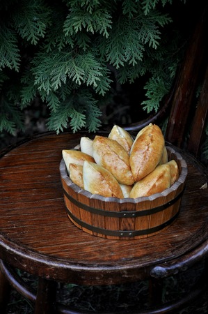Russian patties with apples in a wooden tub on a wooden chairの写真素材