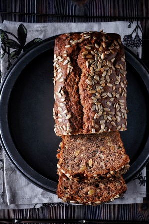 Banana cake with seeds and raisins on a metal dish and cotton napkins. Wooden table. Dark backgroundの写真素材
