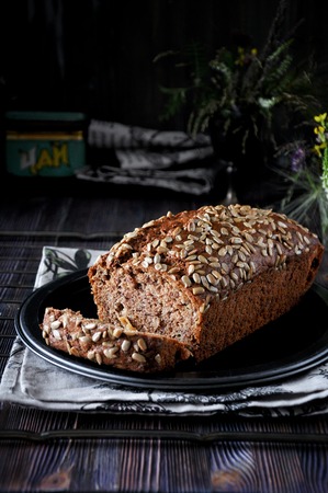 Banana cake with seeds and raisins on a metal dish and cotton napkins. Wooden table. Dark backgroundの写真素材
