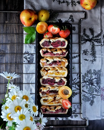 Patties with a lattice made of dough. Stuffing from strawberries, apricots, nectarines, peaches, cherries. On a grillの写真素材