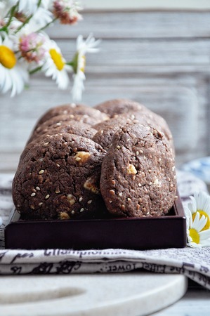 Cookies with cocoa, white chocolate and fried sesame seeds. Background chamomilesの写真素材