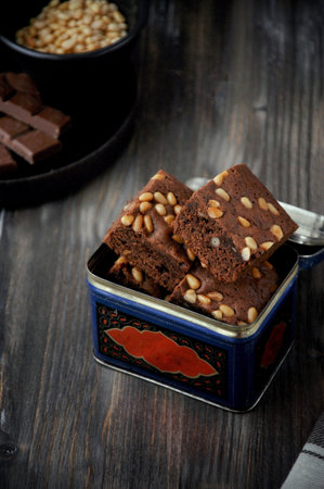 Brownie with pine nuts. Dark background. Rustic style