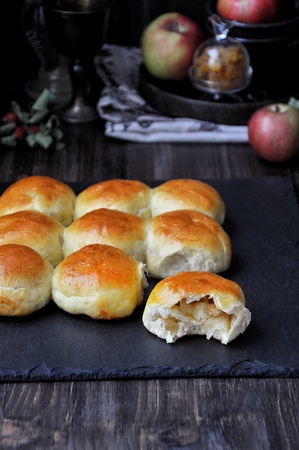 Buns of yeast dough stuffed with apples and raisins. Dark background, fresh applesの写真素材