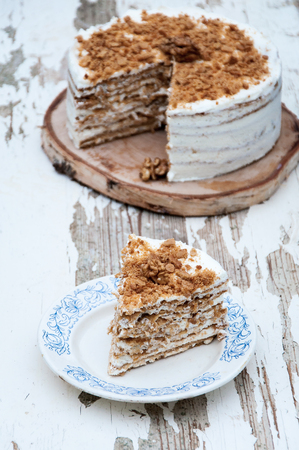 On a wooden background a honey cake with walnuts in a cut. Rustic styleの写真素材