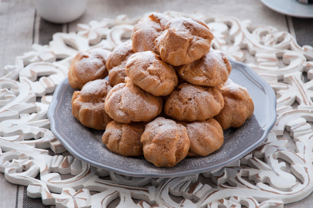 On the table there is a plate of profiteroles, a sweet dessert for breakfastの写真素材