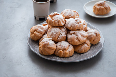 On the table there is a plate of profiteroles, a sweet dessert for breakfastの写真素材