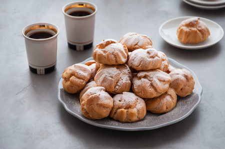 On the table there is a plate of profiteroles, a sweet dessert for breakfastの写真素材
