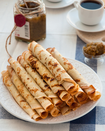 Thin pancakes for breakfast. Maslenitsa. On the table, a dish with pancakes, coffee and jam from feijoaの写真素材