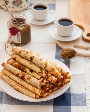 Thin pancakes for breakfast. Maslenitsa. On the table, a dish with pancakes, coffee and jam from feijoaの写真素材