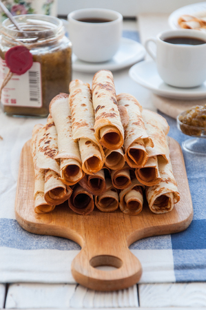 Thin pancakes for breakfast. Maslenitsa. On the table, a dish with pancakes, coffee and jam from feijoaの写真素材