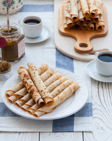 Thin pancakes for breakfast. Maslenitsa. On the table, a dish with pancakes, coffee and jam from feijoaの写真素材
