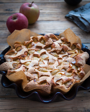 On a wooden table in the form for a baking apple pie from the air dough and fresh apples. Charlotte. Apple strudelの写真素材