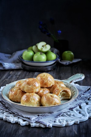 Half of apples baked in dough, buns with apples. Dark background. Decorated with fresh green applesの写真素材