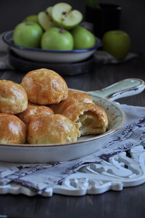 Half of apples baked in dough, buns with apples. Dark background. Decorated with fresh green applesの写真素材