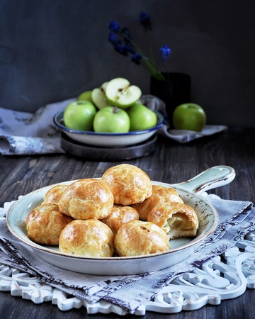 Half of apples baked in dough, buns with apples. Dark background. Decorated with fresh green applesの写真素材