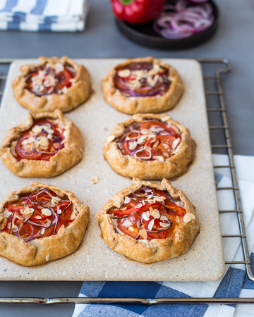 Mini pizza, vegetable galette with cream cheese, red onion, tomatoes, sweet pepper and almondsの写真素材