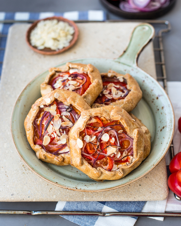 Mini pizza, vegetable galette with cream cheese, red onion, tomatoes, sweet pepper and almondsの写真素材