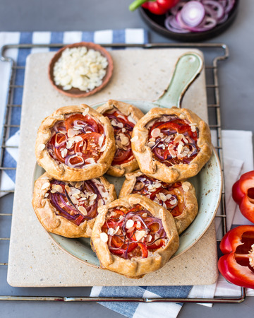 Mini pizza, vegetable galette with cream cheese, red onion, tomatoes, sweet pepper and almondsの写真素材