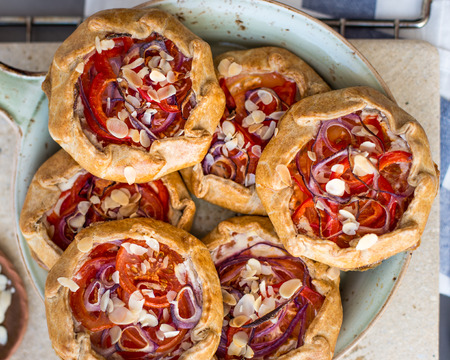 Mini pizza, vegetable galette with cream cheese, red onion, tomatoes, sweet pepper and almondsの写真素材