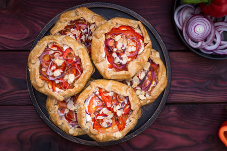 Mini pizza, vegetable galette with cream cheese, red onion, tomatoes, sweet pepper and almondsの写真素材
