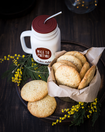 Homemade cookies with sesame seeds and pine nuts, decorated with mimosa flowers. Wooden backgroundの写真素材